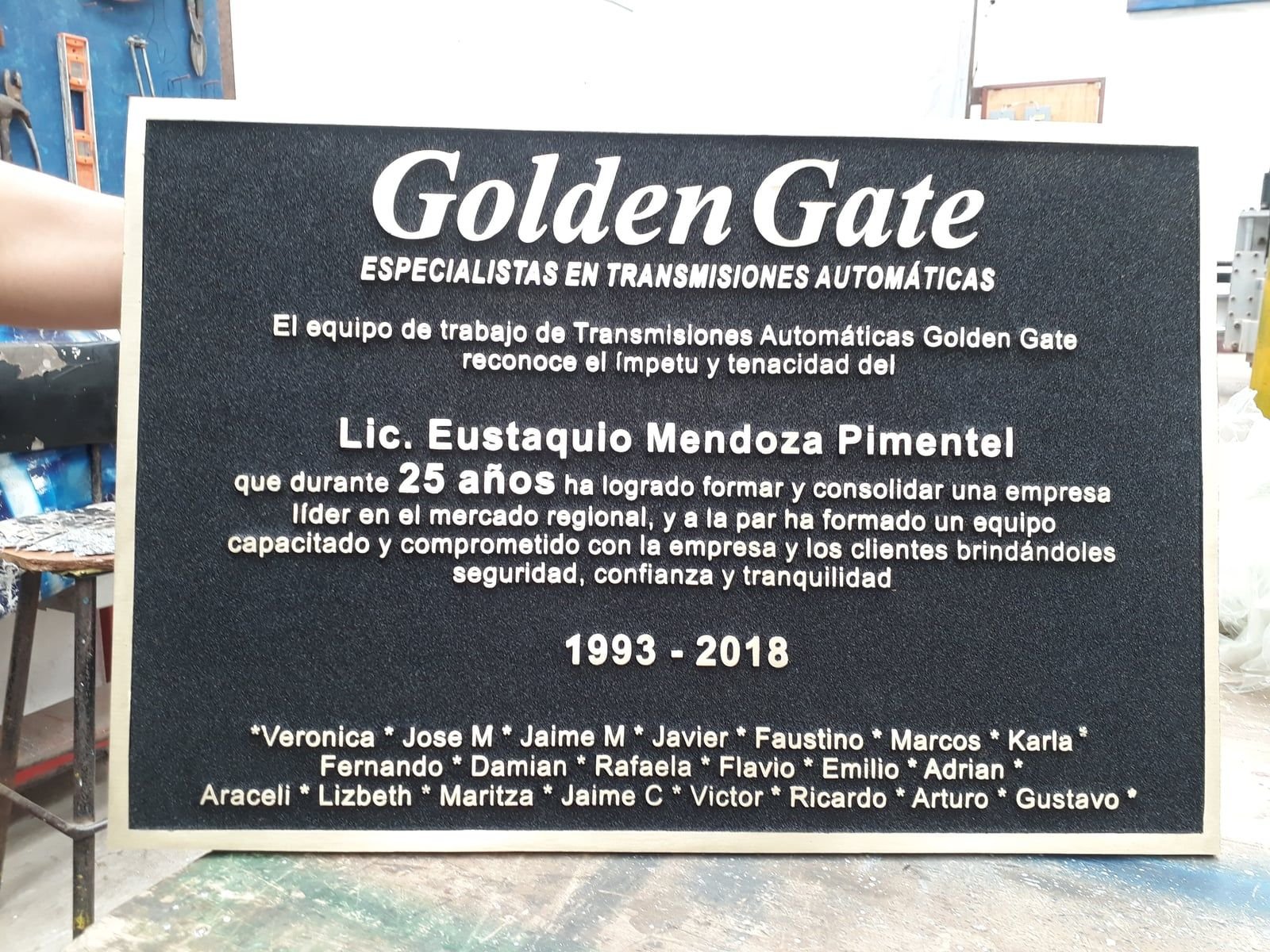 Placa conmemorativa de 25 años fundida en bronce para Transmisiones Automáticas Golden Gate, con texto en relieve sobre fondo negro