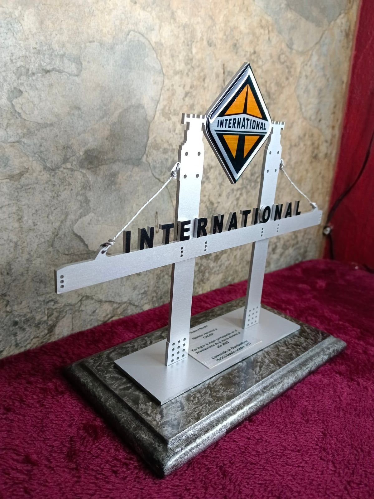 Reconocimiento International de Navistar en aluminio cortado con letras negras, logotipo a color, placa grabada y base de madera